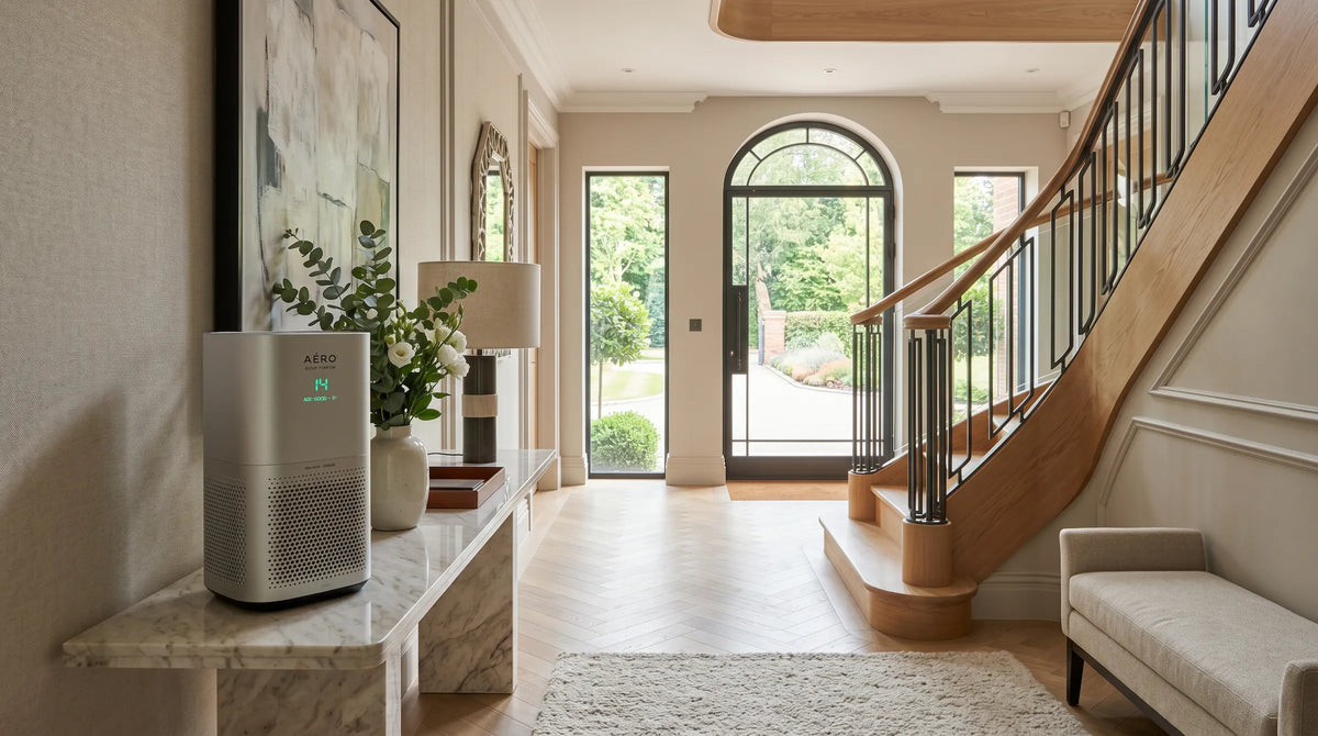 Air purifier on a marble console table in a modern living room with a staircase and large windows.